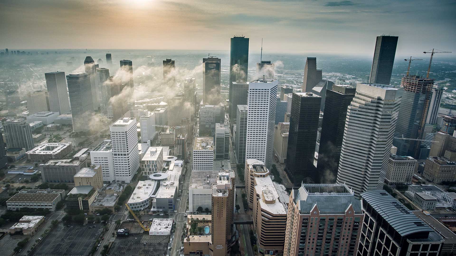 Aerial view of skyscrapers in Houston's downtown core as steam rises from some buildings